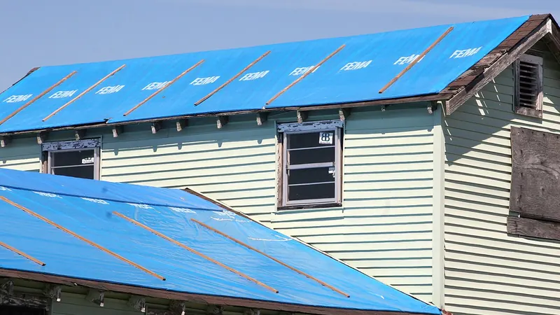 Blue tarps secured over a storm-damaged roof