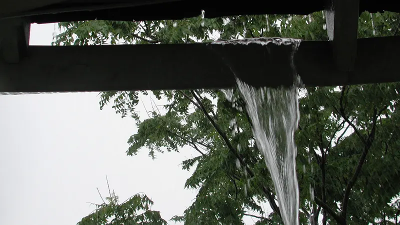Rainwater pouring over a roof edge in a heavy storm