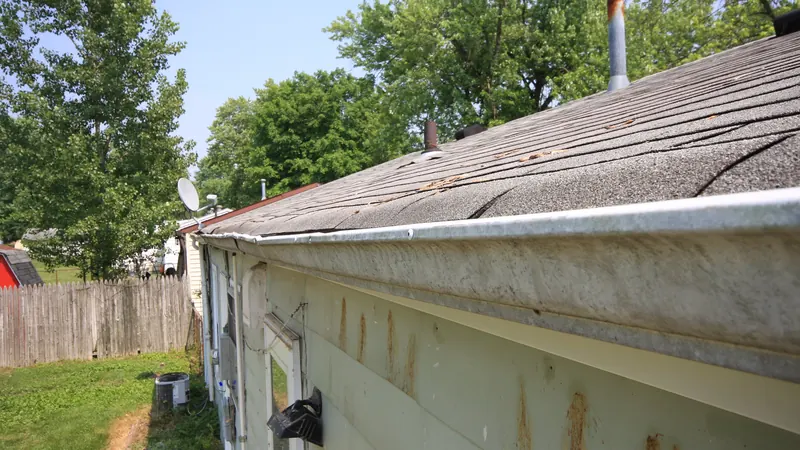 Aluminum gutter along a shingled roof edge